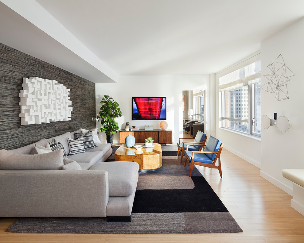 This is an example of a contemporary games room in New York with white walls, light hardwood flooring and a wall mounted tv.