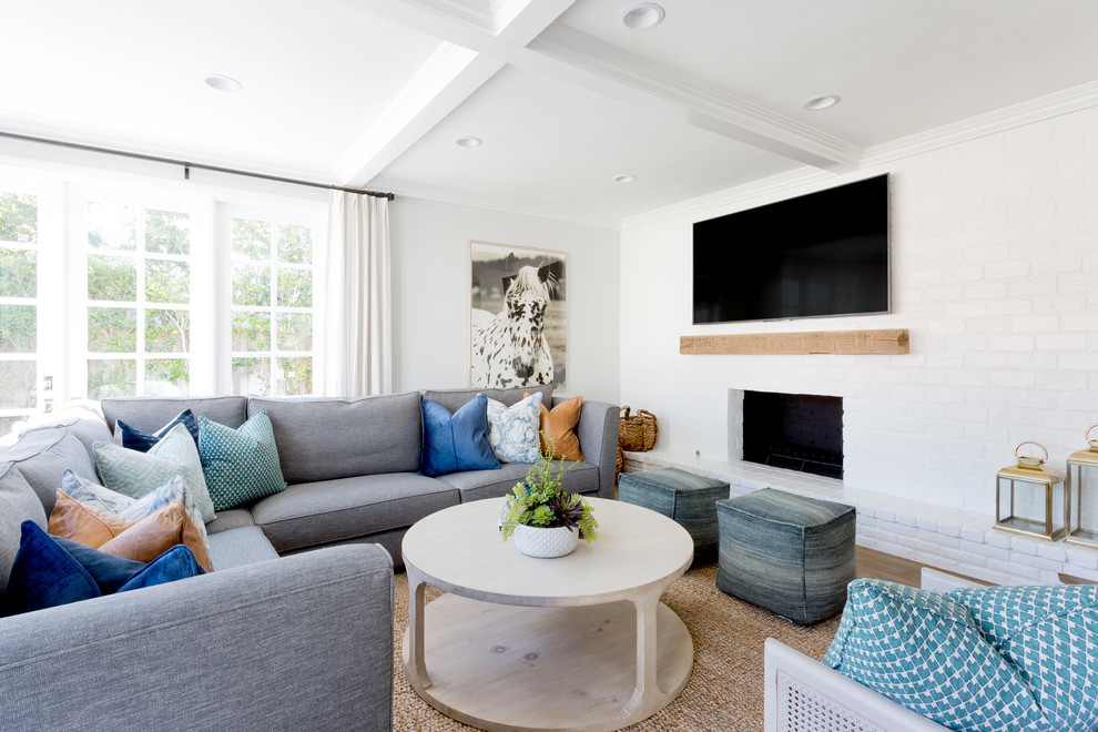 Design ideas for a coastal games room in Orange County with white walls, a ribbon fireplace, a brick fireplace surround and a wall mounted tv.
