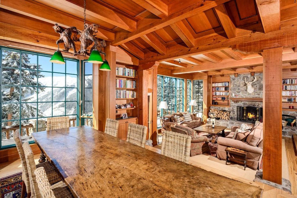 Inspiration for an expansive rustic open plan games room in Denver with a reading nook, a standard fireplace, brown walls, a stone fireplace surround, no tv, brown floors and light hardwood flooring.