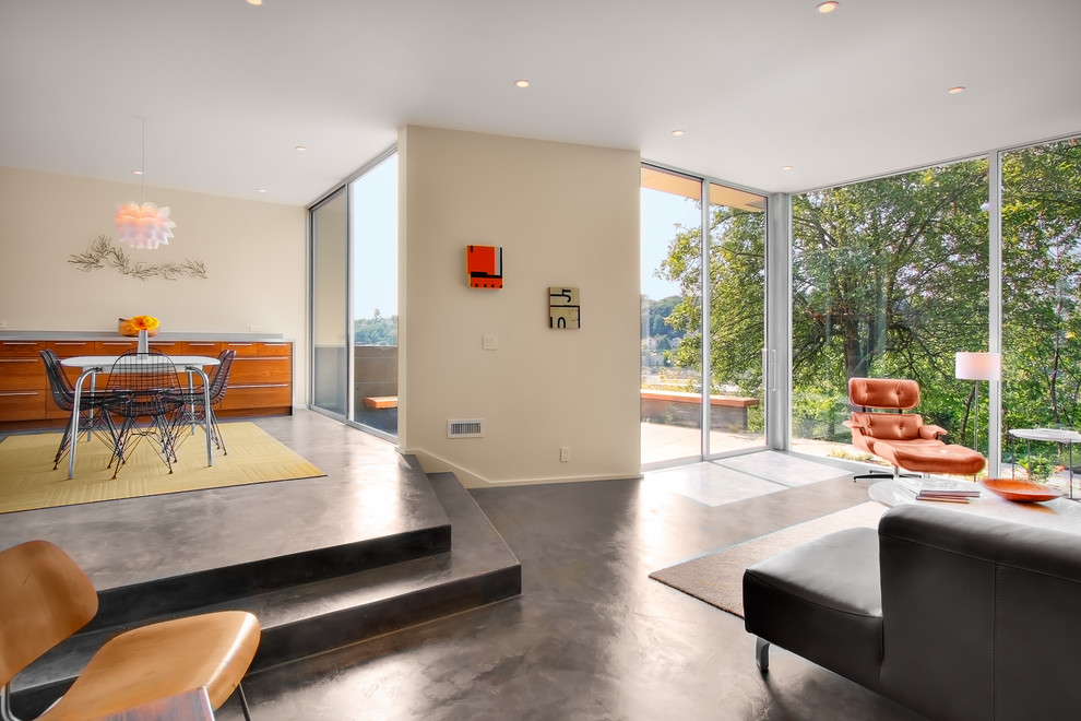 Diseño de sala de estar abierta moderna con paredes beige y suelo de cemento