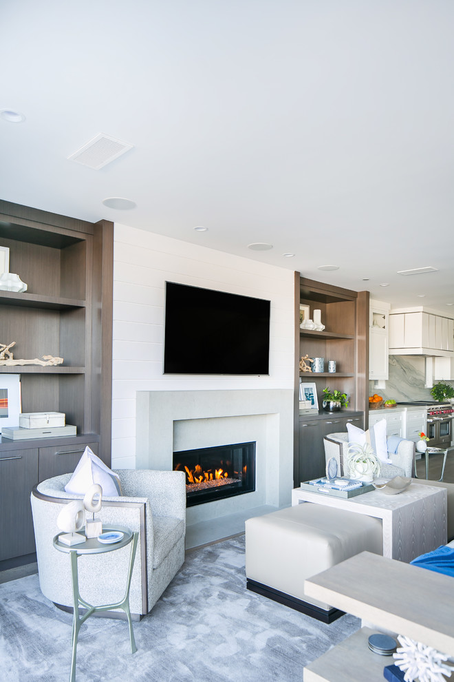 Modelo de sala de estar abierta tradicional con paredes blancas, suelo de madera clara, todas las chimeneas, marco de chimenea de hormigón y televisor colgado en la pared