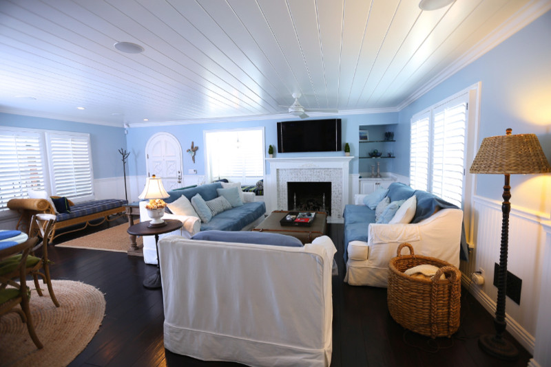 Großes, Offenes Maritimes Wohnzimmer mit blauer Wandfarbe, dunklem Holzboden, Kamin, gefliester Kaminumrandung, TV-Wand und braunem Boden in Orange County