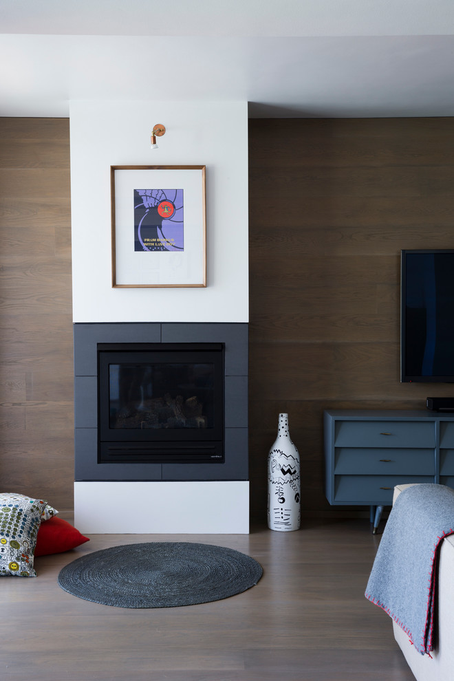 Modelo de sala de estar bohemia con suelo de madera clara, marco de chimenea de baldosas y/o azulejos y televisor colgado en la pared
