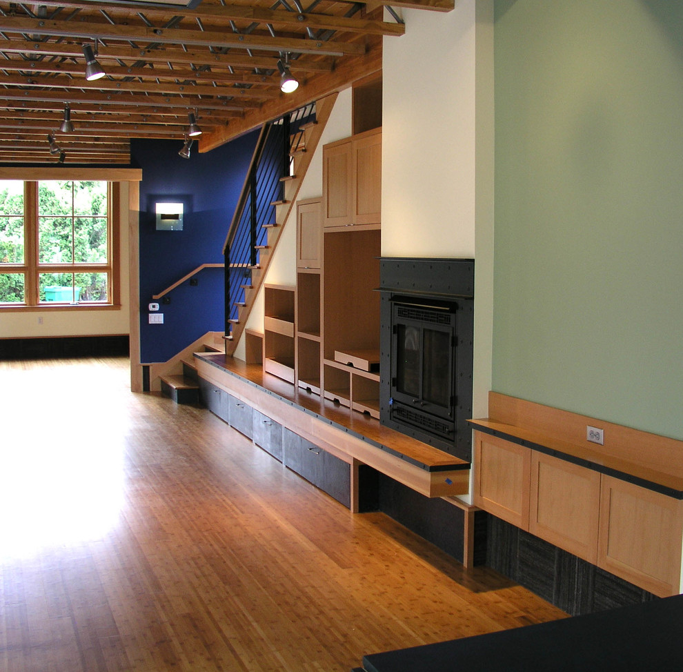 Foto de sala de estar abierta actual grande con paredes azules, suelo de madera en tonos medios y todas las chimeneas