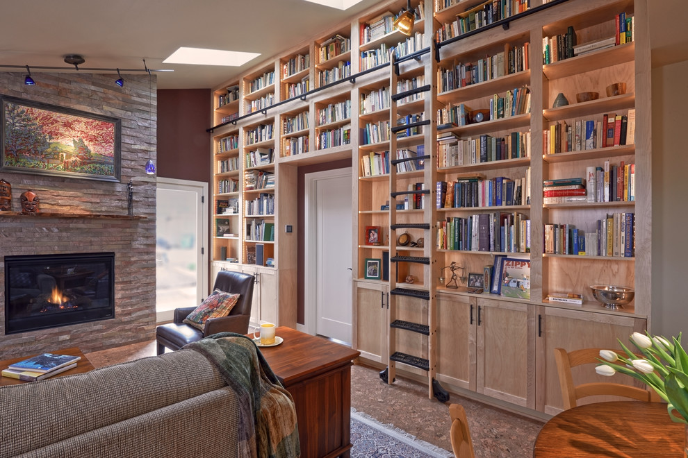 Aménagement d'une salle de séjour craftsman de taille moyenne et ouverte avec une bibliothèque ou un coin lecture, un mur rouge, un sol en liège, une cheminée standard, un manteau de cheminée en pierre, aucun téléviseur et un sol marron.