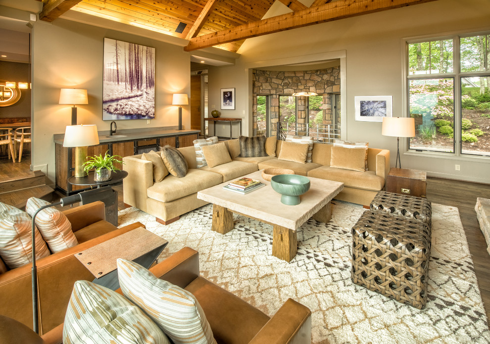 Example of a large mountain style open concept medium tone wood floor and brown floor family room design in Charlotte with beige walls, a standard fireplace, a stone fireplace and a wall-mounted tv