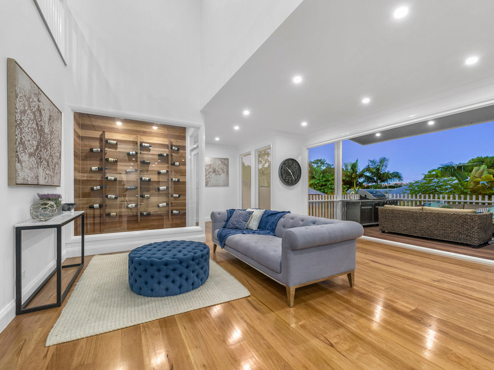 This is an example of a medium sized traditional games room in Brisbane with a home bar, white walls, medium hardwood flooring and brown floors.