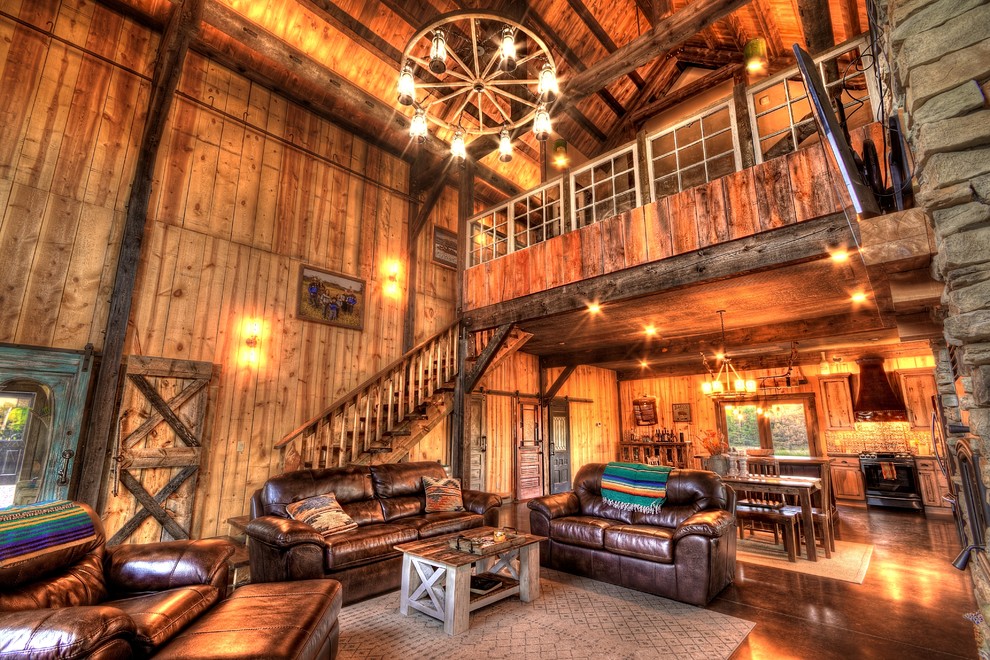 Inspiration for a medium sized rustic mezzanine games room in Other with brown walls, concrete flooring, a two-sided fireplace, a stone fireplace surround, a wall mounted tv and brown floors.