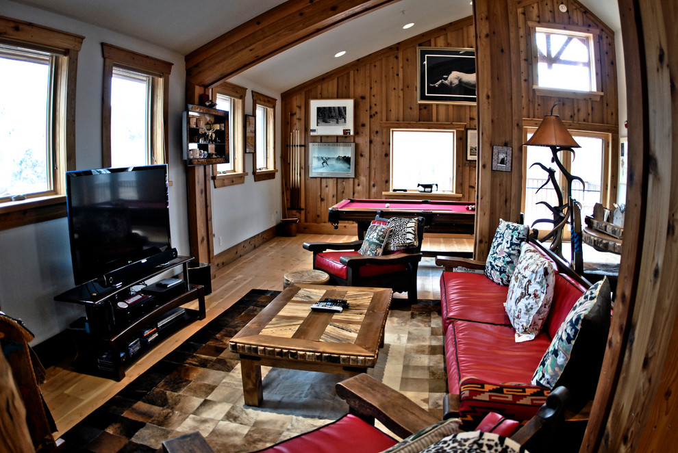 Modelo de sala de estar abierta rural de tamaño medio con paredes blancas, suelo de madera clara y televisor independiente