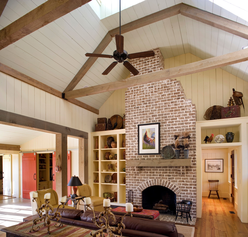 Idée de décoration pour une salle de séjour champêtre ouverte avec un mur beige, un sol en bois brun, une cheminée standard, un manteau de cheminée en brique et éclairage.