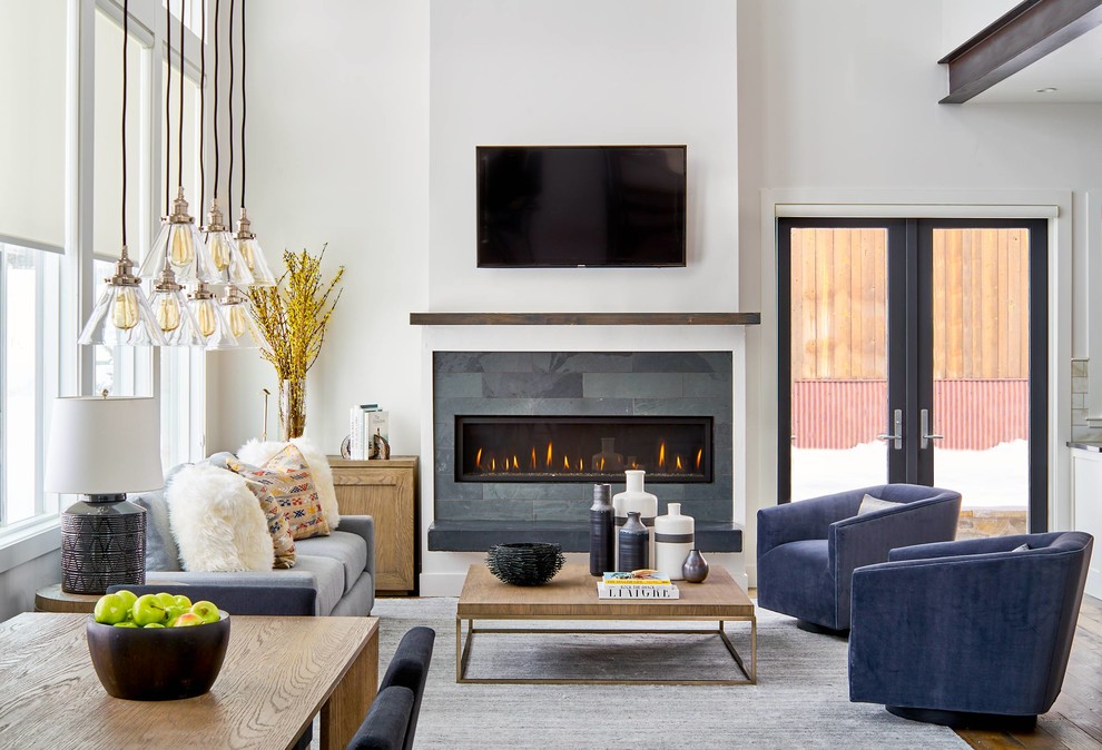 Offenes Modernes Wohnzimmer mit weißer Wandfarbe, braunem Holzboden, Gaskamin, gefliester Kaminumrandung und TV-Wand in Denver
