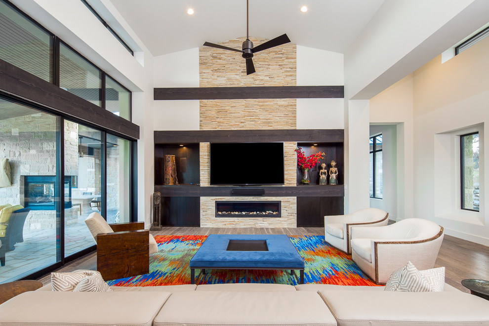 Diseño de sala de estar contemporánea extra grande con paredes blancas, suelo de madera en tonos medios, chimenea lineal, marco de chimenea de baldosas y/o azulejos, televisor colgado en la pared y suelo marrón