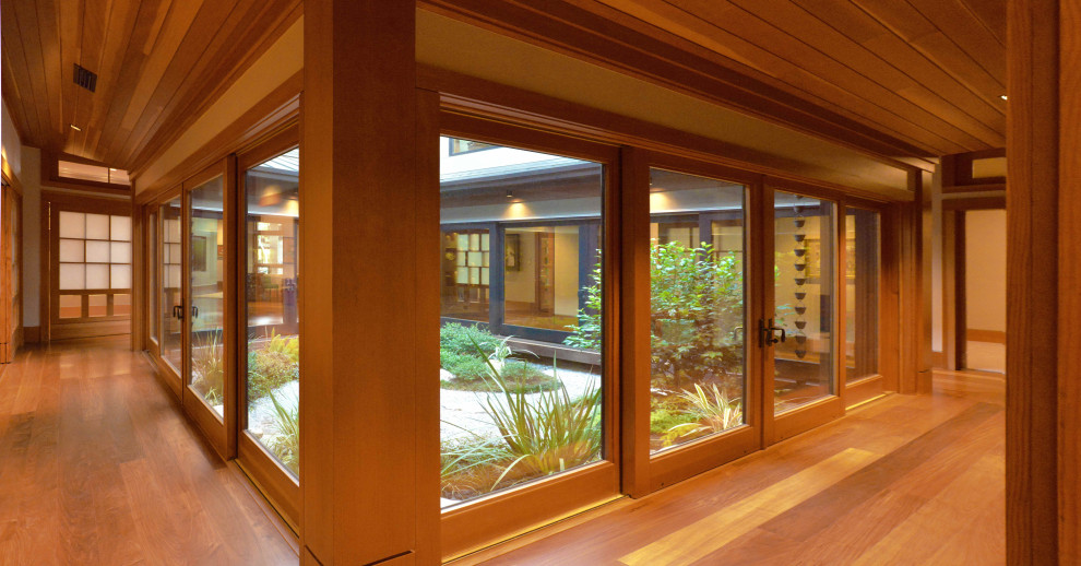 Imagen de sala de estar abierta de estilo zen grande con suelo de madera en tonos medios, paredes marrones y suelo marrón