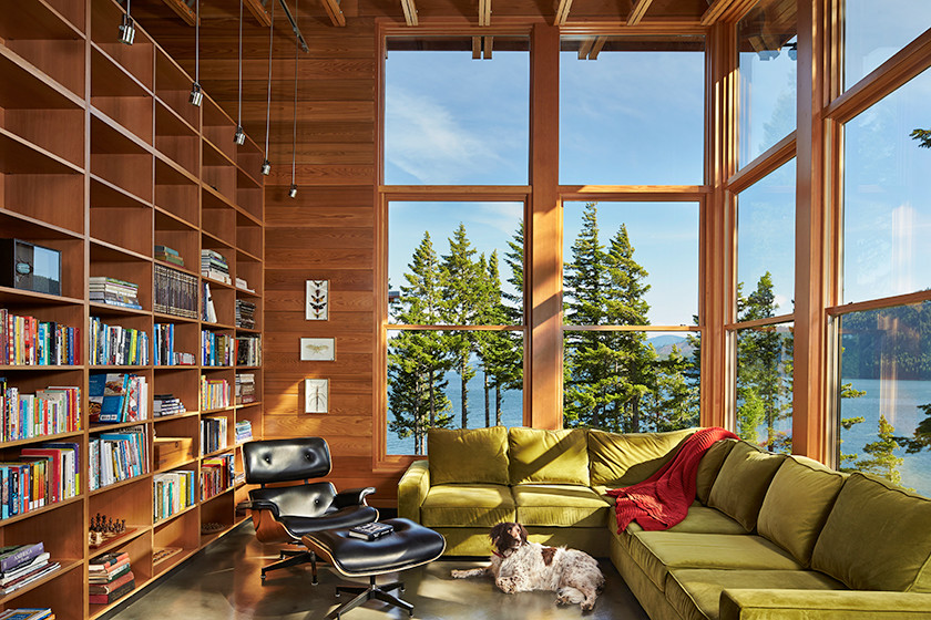 Immagine di un grande soggiorno minimalista aperto con libreria, pareti marroni, pavimento in cemento, nessun camino e nessuna TV