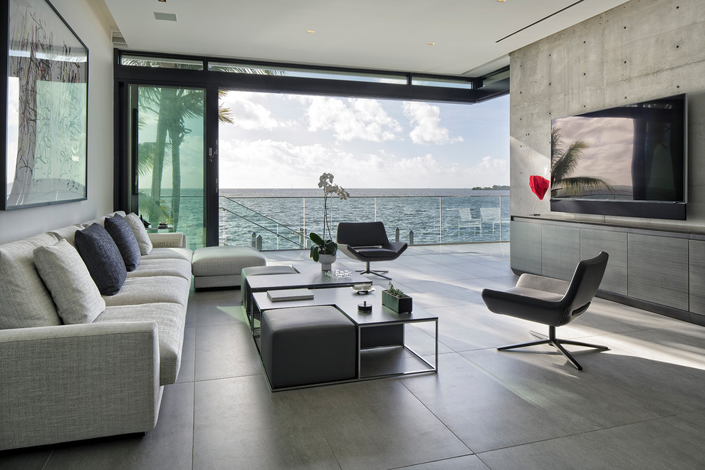 Offenes Modernes Wohnzimmer ohne Kamin mit grauer Wandfarbe, Keramikboden, TV-Wand und grauem Boden in Miami