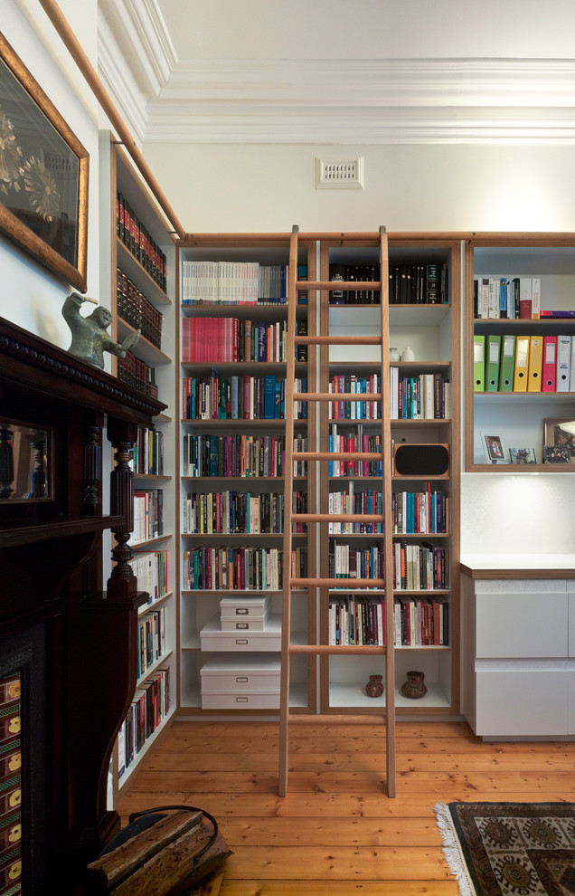 Mittelgroße, Fernseherlose Moderne Bibliothek ohne Kamin mit weißer Wandfarbe und braunem Holzboden in Melbourne