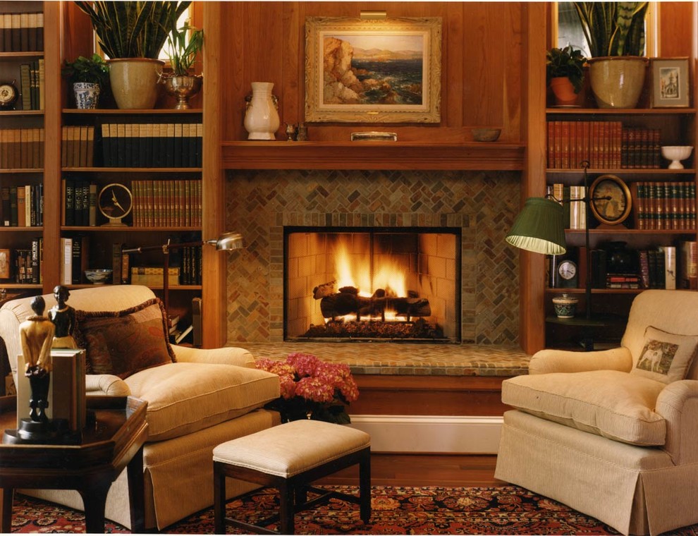 Imagen de sala de estar con biblioteca cerrada tradicional de tamaño medio sin televisor con paredes marrones, suelo de madera en tonos medios, todas las chimeneas, marco de chimenea de baldosas y/o azulejos y suelo marrón