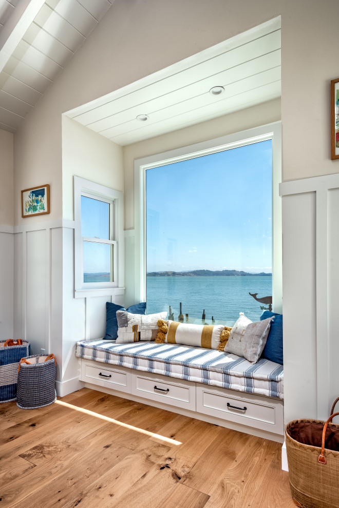 Imagen de sala de estar abierta costera de tamaño medio con paredes beige, suelo de madera en tonos medios y suelo beige