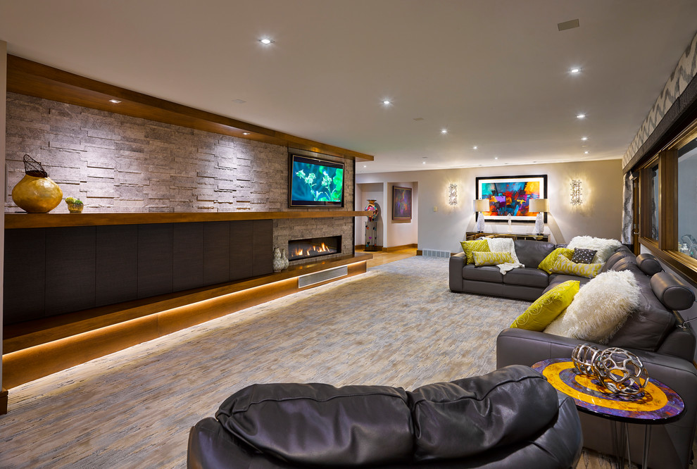 Foto de sala de estar abierta actual de tamaño medio con paredes grises, moqueta, chimenea lineal, marco de chimenea de piedra, televisor colgado en la pared y suelo multicolor