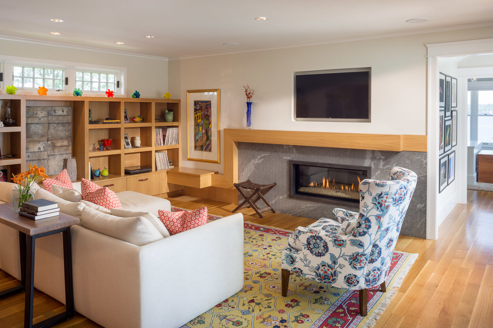 Imagen de sala de estar cerrada clásica renovada de tamaño medio con paredes blancas, suelo de madera en tonos medios, chimenea lineal, marco de chimenea de metal y televisor colgado en la pared
