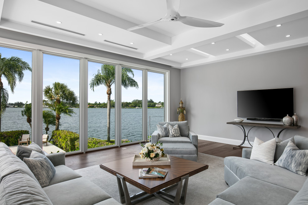 Photo of an expansive contemporary open plan games room in Tampa with grey walls, dark hardwood flooring, a wall mounted tv, brown floors and a drop ceiling.