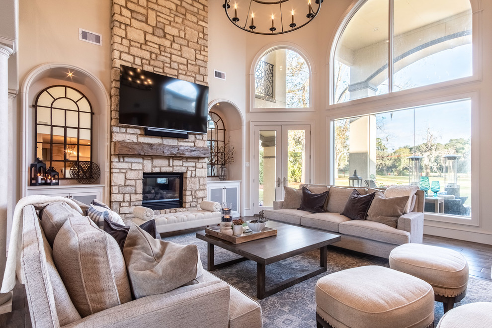 Large open concept porcelain tile and brown floor family room photo in Houston with a two-sided fireplace, a stone fireplace and a wall-mounted tv