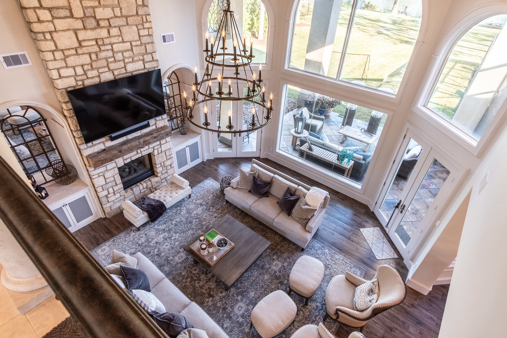 Large open plan games room in Houston with porcelain flooring, a two-sided fireplace, a stone fireplace surround, a wall mounted tv and brown floors.