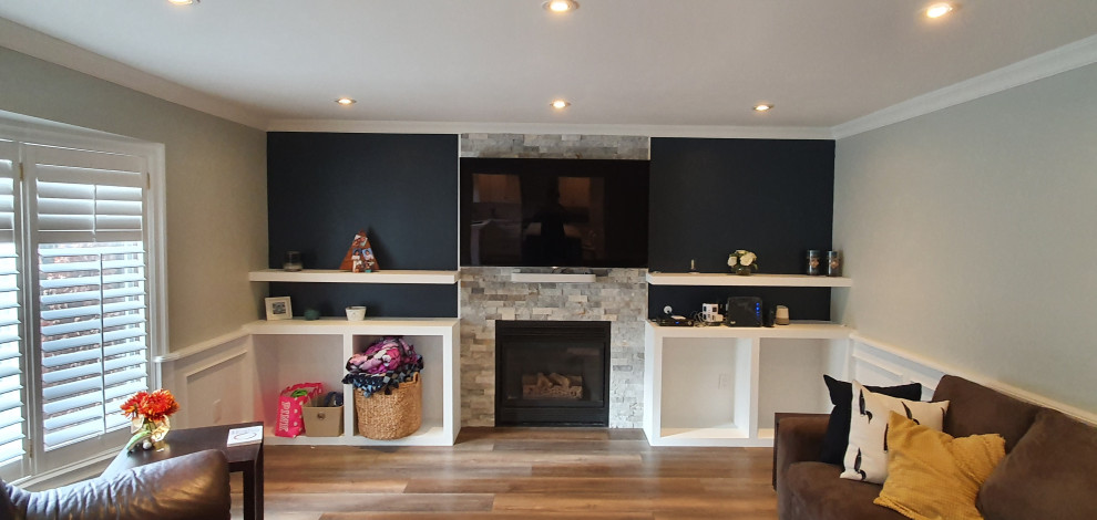 Стильный дизайн: гостиная комната в современном стиле с полом из ламината, стандартным камином и фасадом камина из каменной кладки - последний тренд