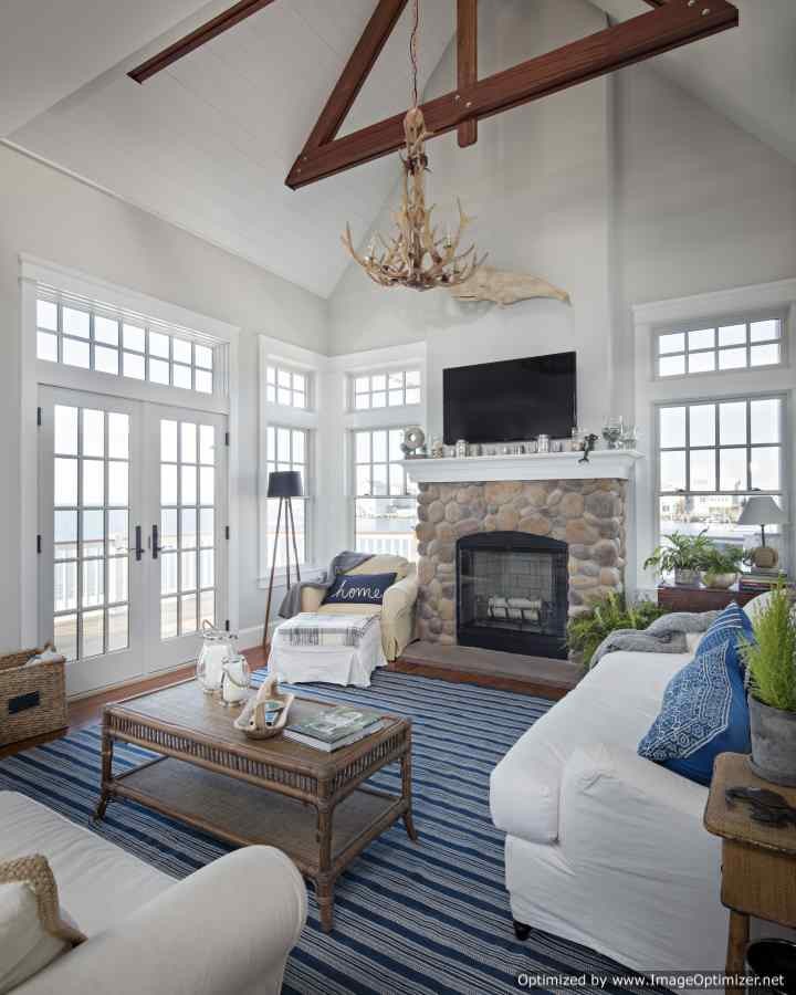 Inspiration for a mid-sized coastal open concept medium tone wood floor family room remodel in Philadelphia with white walls, a standard fireplace, a stone fireplace and a wall-mounted tv