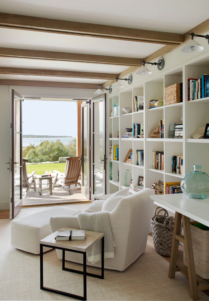 Imagen de sala de estar con biblioteca abierta marinera sin chimenea y televisor con paredes blancas, suelo de madera en tonos medios y suelo marrón