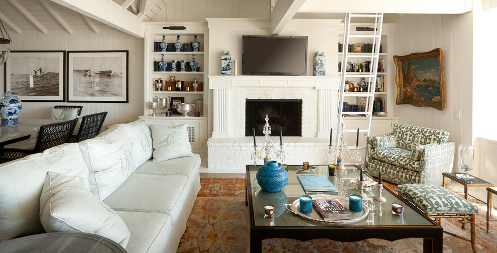 Immagine di un soggiorno stile marinaro di medie dimensioni e aperto con pareti bianche, camino classico, cornice del camino in mattoni e TV a parete