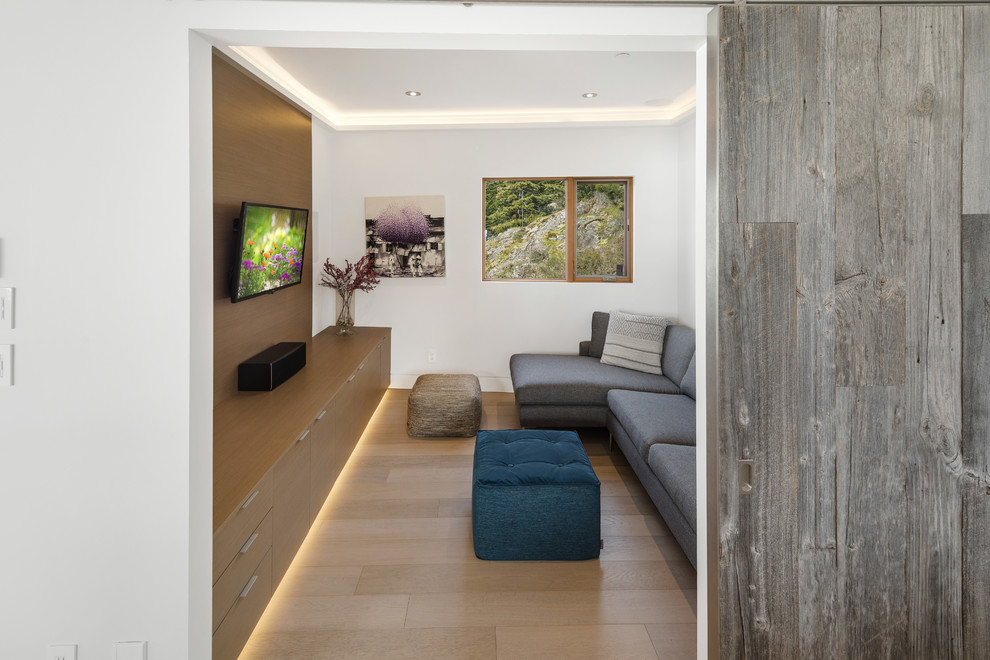 Ispirazione per un soggiorno design con pareti bianche, parquet chiaro, TV a parete e pavimento beige
