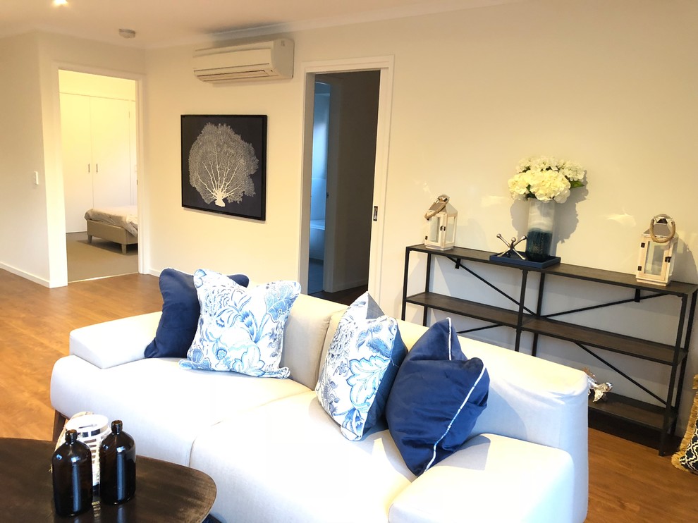 Immagine di un soggiorno stile marino di medie dimensioni e aperto con pareti bianche, pavimento in laminato e pavimento marrone
