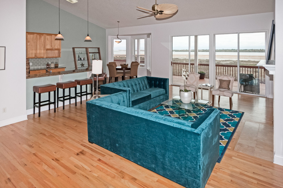 Пример оригинального дизайна: большая открытая гостиная комната в морском стиле с синими стенами, светлым паркетным полом, стандартным камином и фасадом камина из камня