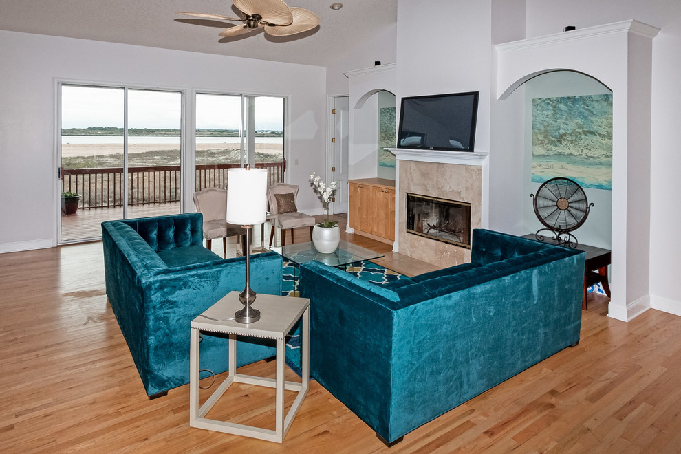 This is an example of a large coastal open plan games room in Jacksonville with blue walls, light hardwood flooring, a standard fireplace and a stone fireplace surround.