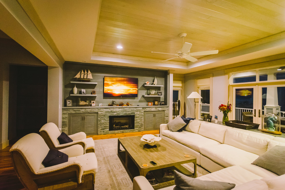 Modelo de sala de estar con rincón musical tipo loft marinera grande con suelo de madera clara, todas las chimeneas, marco de chimenea de ladrillo, televisor colgado en la pared y suelo marrón