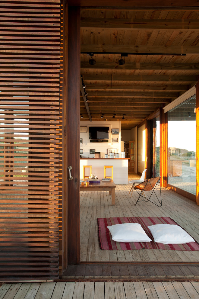 Immagine di un soggiorno costiero aperto con pavimento in legno massello medio e tappeto