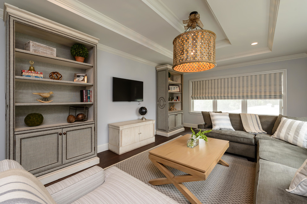 Modelo de sala de estar tradicional renovada con paredes grises, suelo de madera oscura y televisor colgado en la pared