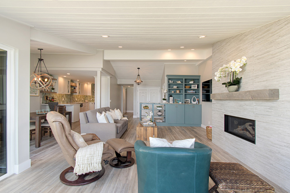 Medium sized coastal open plan games room in San Diego with grey walls, vinyl flooring, a standard fireplace, a tiled fireplace surround, a wall mounted tv and grey floors.