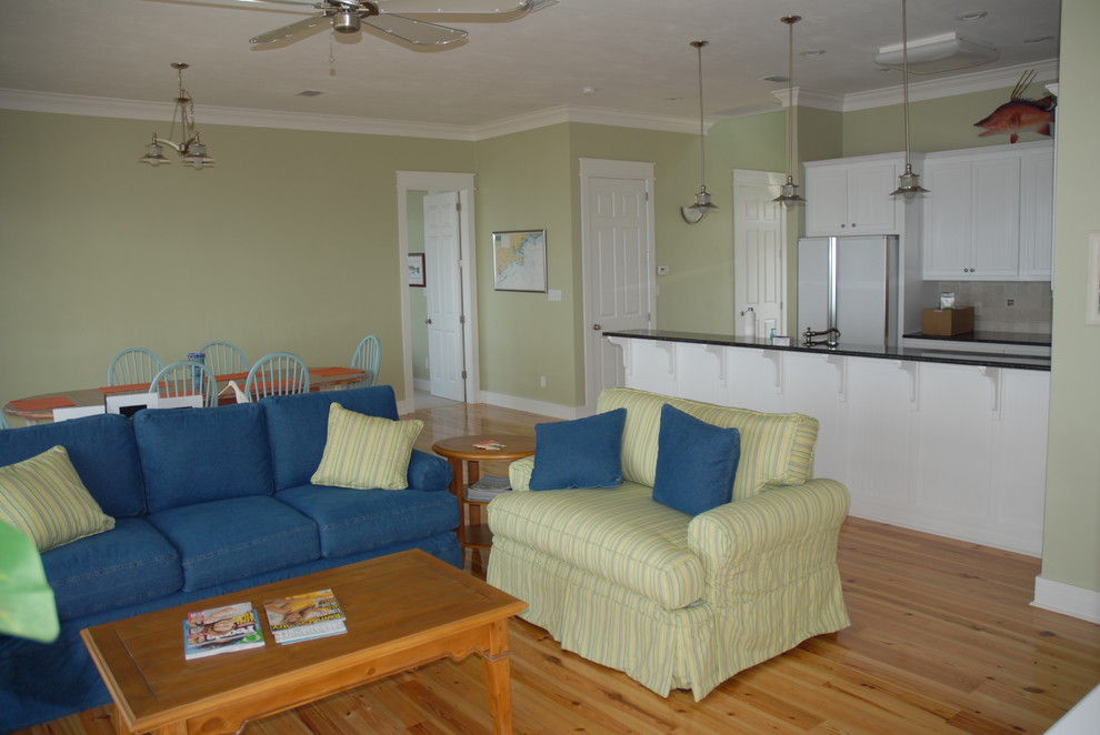 Aménagement d'une salle de séjour bord de mer de taille moyenne et ouverte avec un mur vert, parquet clair et un sol beige.