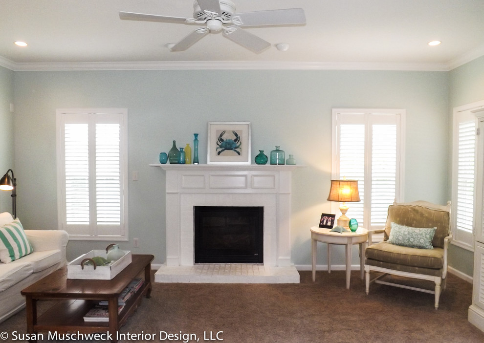 Modelo de sala de estar abierta costera de tamaño medio con paredes azules, moqueta, todas las chimeneas, marco de chimenea de ladrillo y televisor retractable