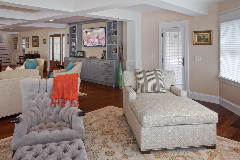 Modelo de sala de estar abierta clásica renovada grande sin chimenea con paredes beige, suelo de madera oscura, televisor colgado en la pared y suelo marrón