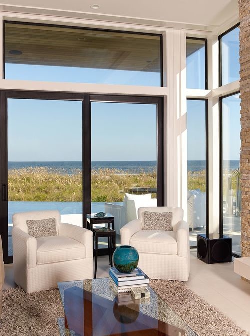 Modelo de sala de estar abierta costera con paredes blancas, moqueta, marco de chimenea de ladrillo y suelo blanco