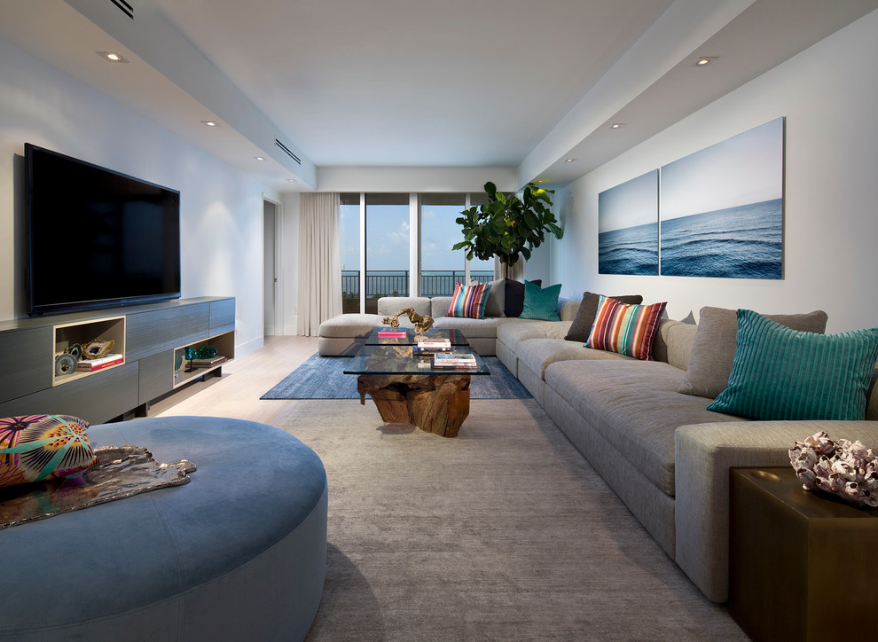 Стильный дизайн: гостиная комната в морском стиле с белыми стенами, светлым паркетным полом и телевизором на стене - последний тренд