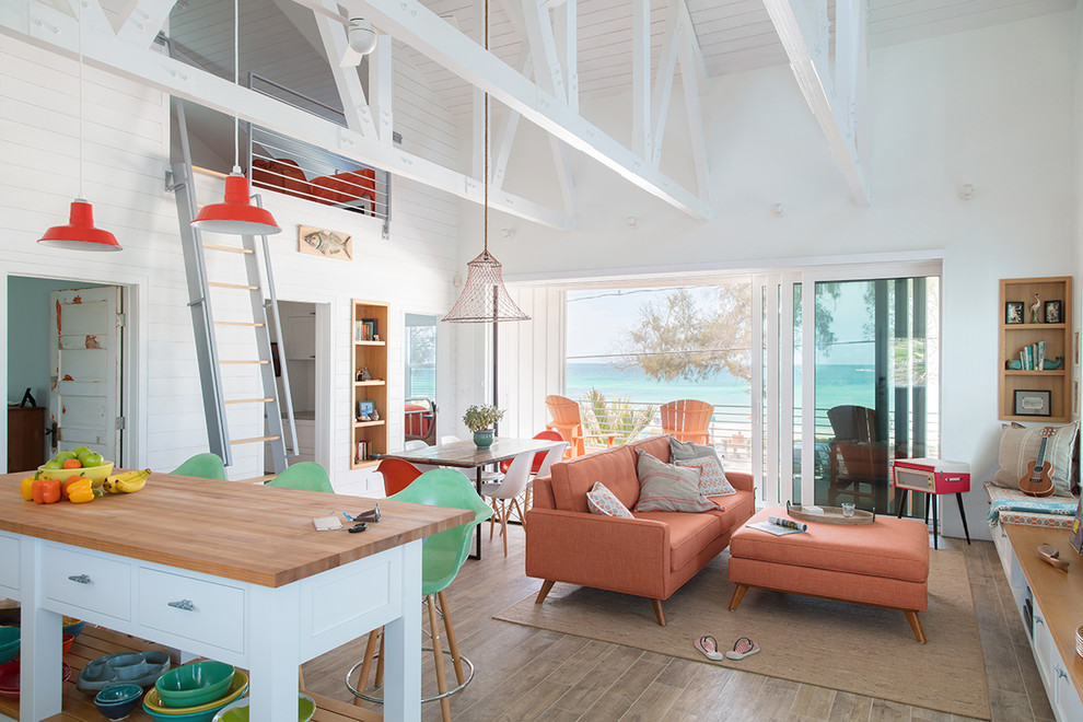 This is an example of a small beach style mezzanine games room in Tampa with white walls and brown floors.