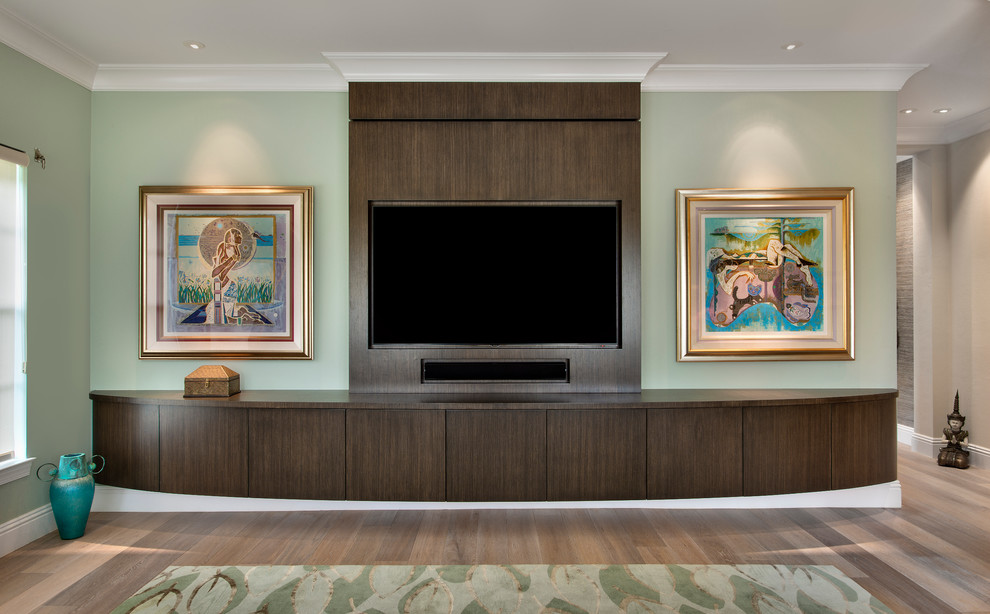 Ejemplo de sala de estar abierta actual de tamaño medio con paredes verdes, suelo de madera clara y pared multimedia