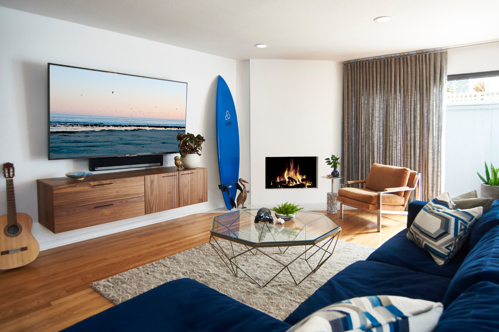 Cette image montre une salle de séjour marine ouverte et de taille moyenne avec un mur blanc, un sol en bois brun, une cheminée ribbon, un manteau de cheminée en plâtre, un téléviseur fixé au mur et un sol marron.