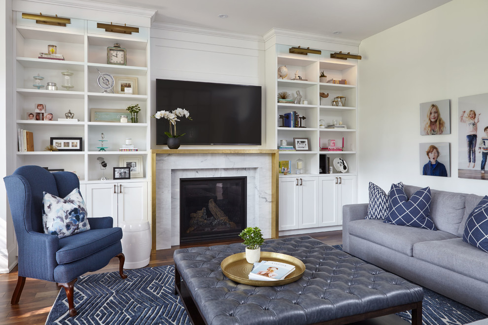 Imagen de sala de estar clásica renovada con paredes blancas, suelo de madera en tonos medios, todas las chimeneas, marco de chimenea de metal, televisor colgado en la pared y suelo marrón