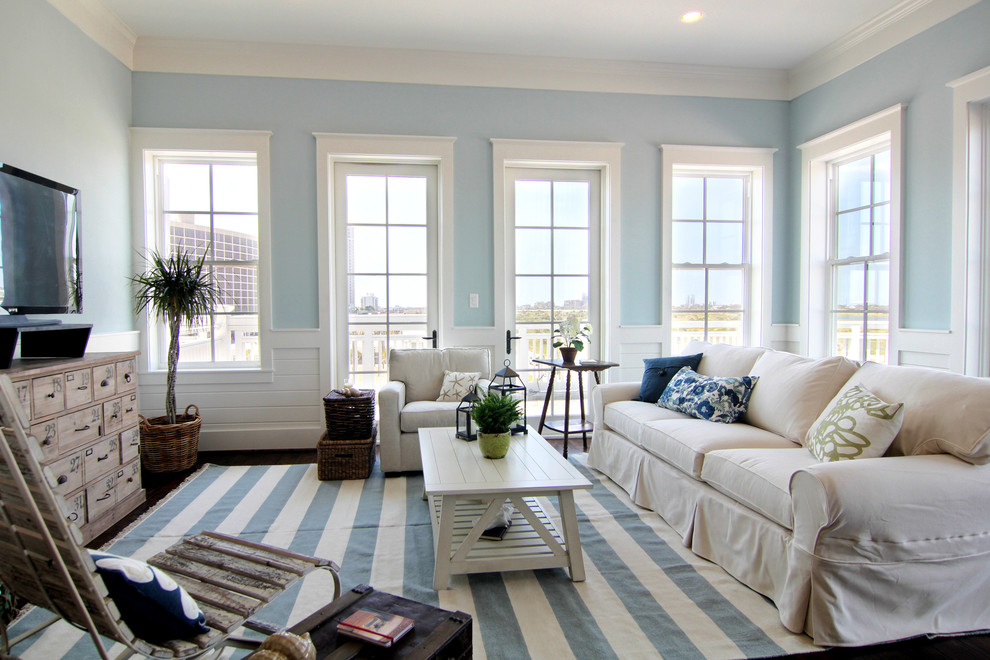 Diseño de sala de estar abierta marinera con paredes azules, moqueta, televisor independiente y suelo multicolor