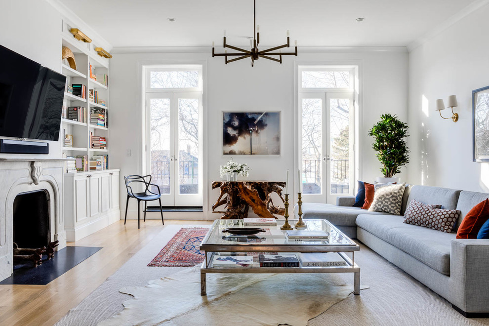 Foto di un soggiorno tradizionale con parquet chiaro, libreria, pareti bianche, camino classico, TV a parete e tappeto